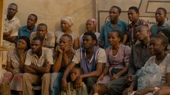 Movie still from “Machine Gun Preacher” (2011), directed by Marc Forster – A group of men and women sitting next to each other; Medium shot, High angle