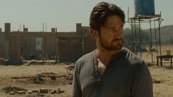Movie still from “Machine Gun Preacher” (2011), directed by Marc Forster – A person standing in front of a building; Close Up shot, Over the shoulder angle