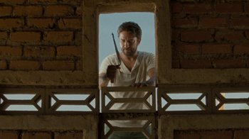 Movie still from “Machine Gun Preacher” (2011), directed by Marc Forster – A man holding a knife in a window frame; Medium shot, Low angle