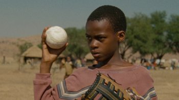 Movie still from “Machine Gun Preacher” (2011), directed by Marc Forster – A young boy holding a baseball and a baseball glove; Close Up shot, Low angle