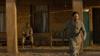 Movie still from “Machine Gun Preacher” (2011), directed by Marc Forster – Two men sitting in front of a brick building; Wide shot, Over the shoulder angle