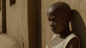 Movie still from “Machine Gun Preacher” (2011), directed by Marc Forster – A person with a shaved head is standing in front of a wall; Close Up shot, Low angle