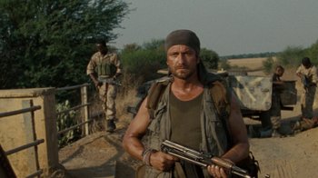 Movie still from “Machine Gun Preacher” (2011), directed by Marc Forster – A man holding a gun while standing next to another man; Medium shot, Low angle