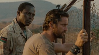 Movie still from “Machine Gun Preacher” (2011), directed by Marc Forster – Two men standing next to each other in front of a fence; Close Up shot, Over the shoulder angle