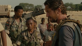 Movie still from “Machine Gun Preacher” (2011), directed by Marc Forster – A group of men standing next to each other on a dirt field; Medium shot, Over the shoulder angle