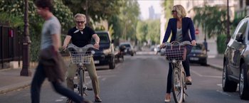 Movie still from “Madame” (2017), directed by Amanda Sthers – A man and a woman riding bikes down a street; Wide shot, Over the shoulder angle
