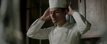 Movie still from “Madame” (2017), directed by Amanda Sthers – A man in a chef's outfit adjusts his hat; Close Up shot, Low angle