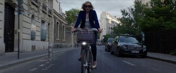 Movie still from “Madame” (2017), directed by Amanda Sthers – A woman riding a bike down a street; Wide shot, High angle