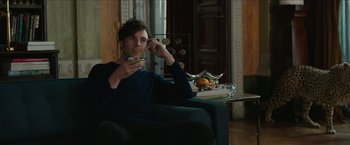 Movie still from “Madame” (2017), directed by Amanda Sthers – A man sitting on a couch holding a cup of coffee; Medium shot, Over the shoulder angle