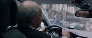 Movie still from “Madame” (2017), directed by Amanda Sthers – An older man driving a car in the street; Close Up shot, Over the shoulder angle