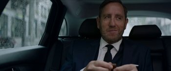 Movie still from “Madame” (2017), directed by Amanda Sthers – A person sitting in a car holding a cigar; Close Up shot, Over the shoulder angle