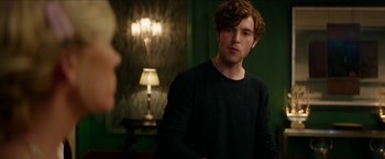 Movie still from “Madame” (2017), directed by Amanda Sthers – A young man standing next to a lamp in front of a green wall; Medium shot, Over the shoulder angle