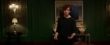 Movie still from “Madame” (2017), directed by Amanda Sthers – A man standing in front of a green wall holding his hands out; Medium shot, Over the shoulder angle