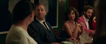 Movie still from “Madame” (2017), directed by Amanda Sthers – A man sitting at a table with two other people; Medium shot, Over the shoulder angle