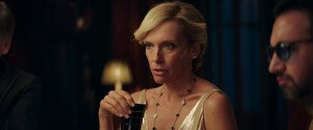 Movie still from “Madame” (2017), directed by Amanda Sthers – A woman in a gold dress holding a bottle of wine; Close Up shot, Over the shoulder angle