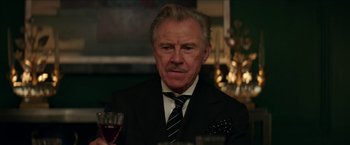 Movie still from “Madame” (2017), directed by Amanda Sthers – An older man wearing a suit and tie holding a glass of wine; Close Up shot, Over the shoulder angle