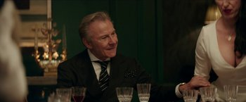Movie still from “Madame” (2017), directed by Amanda Sthers – An older man sitting at a table with three wine glasses in front of him; Close Up shot, Over the shoulder angle