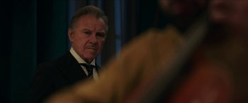 Movie still from “Madame” (2017), directed by Amanda Sthers – An older man wearing a suit and tie looking at the camera; Close Up shot, Over the shoulder angle