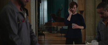 Movie still from “Madame” (2017), directed by Amanda Sthers – A man holding a glass and talking on a cell phone; Medium shot, Over the shoulder angle