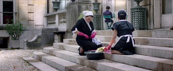 Movie still from “Madame” (2017), directed by Amanda Sthers – A woman wearing pink gloves washing a banana peel; Wide shot, High angle