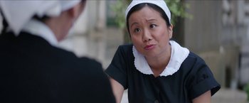 Movie still from “Madame” (2017), directed by Amanda Sthers – A woman in a maid's outfit is sitting in front of a man; Close Up shot, Over the shoulder angle