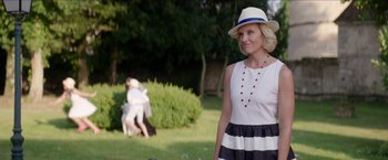 Movie still from “Madame” (2017), directed by Amanda Sthers – A woman wearing a white hat and a black and white striped dress; Medium shot, Over the shoulder angle