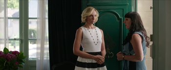 Movie still from “Madame” (2017), directed by Amanda Sthers – Charlize theron in a white top and black skirt; Medium shot, Over the shoulder angle