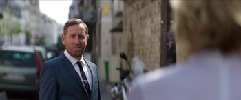 Movie still from “Madame” (2017), directed by Amanda Sthers – A person wearing a suit and tie; Medium shot, Over the shoulder angle