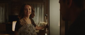 Movie still from “Little Fish” (2020), directed by Chad Hartigan – A woman standing in front of a mirror holding a vase of flowers; Medium shot, Over the shoulder angle