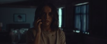 Movie still from “Little Fish” (2020), directed by Chad Hartigan – A woman is talking on a cell phone in a dark room; Close Up shot, Over the shoulder angle