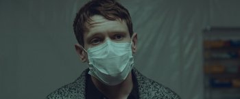 Movie still from “Little Fish” (2020), directed by Chad Hartigan – A man wearing a face mask looking at the camera; Close Up shot, Low angle