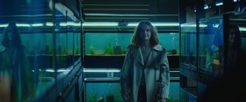 Movie still from “Little Fish” (2020), directed by Chad Hartigan – A woman standing in front of a fish tank; Medium shot, High angle