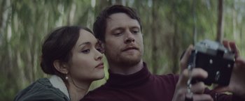 Movie still from “Little Fish” (2020), directed by Chad Hartigan – A man and a woman standing next to each other in a forest; Close Up shot, Low angle