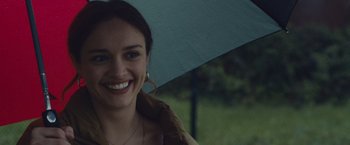 Movie still from “Little Fish” (2020), directed by Chad Hartigan – A smiling woman holding an umbrella over her head; Close Up shot, Over the shoulder angle