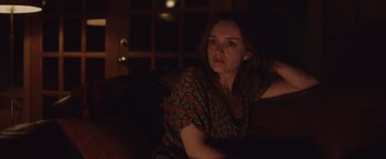 Movie still from “Little Fish” (2020), directed by Chad Hartigan – A woman sitting on a couch in a dark room; Medium shot, Over the shoulder angle
