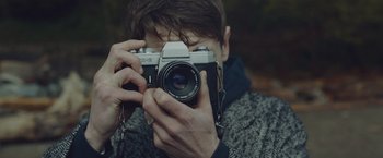 Movie still from “Little Fish” (2020), directed by Chad Hartigan – A man taking a picture with a camera; Extreme Close Up shot, Over the shoulder angle