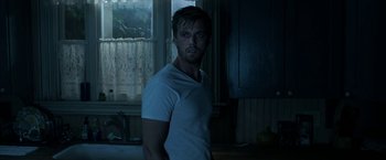 Movie still from “Malignant” (2021), directed by James Wan – A man standing in a dark room in front of a window; Medium shot, Low angle