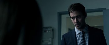 Movie still from “Malignant” (2021), directed by James Wan – A man standing in front of a mirror in a room; Close Up shot, Over the shoulder angle