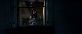 Movie still from “Malignant” (2021), directed by James Wan – A woman in a robe looking out of a window; Medium shot, Low angle