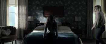 Movie still from “Malignant” (2021), directed by James Wan – A woman sitting on the edge of a bed in the dark; Wide shot, High angle