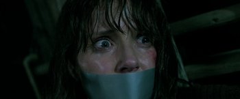 Movie still from “Malignant” (2021), directed by James Wan – A woman with her mouth taped shut with her eyes wide open; Close Up shot, Low angle