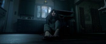 Movie still from “Malignant” (2021), directed by James Wan – A woman sitting on the floor of a kitchen; Wide shot, High angle