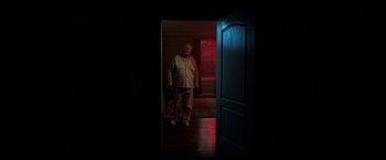 Movie still from “Malignant” (2021), directed by James Wan – An older man standing in a dark room; Wide shot, Low angle