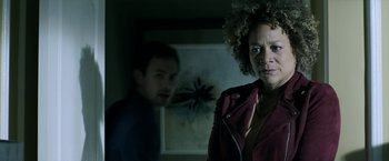 Movie still from “Malignant” (2021), directed by James Wan – A woman and a man in a dark room; Medium shot, Over the shoulder angle