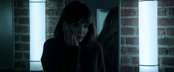 Movie still from “Malignant” (2021), directed by James Wan – A woman is talking on a cell phone in front of a mirror; Close Up shot, Low angle