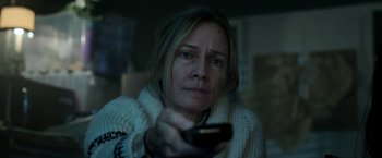 Movie still from “Malignant” (2021), directed by James Wan – A woman holding a remote control in her hand; Close Up shot, Low angle