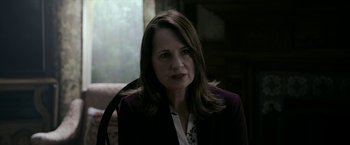 Movie still from “Malignant” (2021), directed by James Wan – A person sitting in a chair wearing a jacket; Close Up shot, Over the shoulder angle