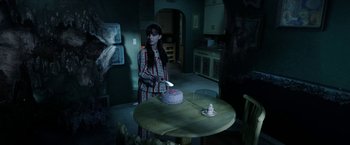 Movie still from “Malignant” (2021), directed by James Wan – A woman standing at a table cutting a cake with a knife; Medium shot, High angle