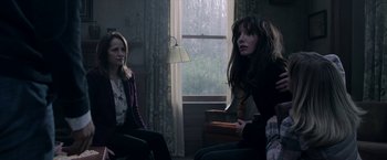 Movie still from “Malignant” (2021), directed by James Wan – Two women sitting in front of a window in a living room; Medium shot, Over the shoulder angle