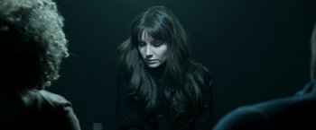 Movie still from “Malignant” (2021), directed by James Wan – A woman with long dark hair sitting in a dark room; Close Up shot, Over the shoulder angle